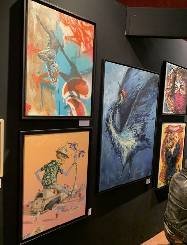 Quatre œuvres d'art colorées exposées sur un mur noir.