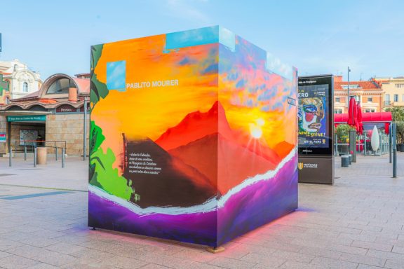 Cube coloré avec un paysage vibrant au coucher de soleil et des éléments graphiques.