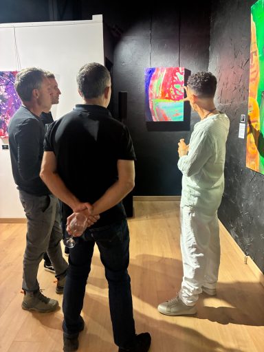 Quatre personnes observent des œuvres d'art colorées dans une galerie.