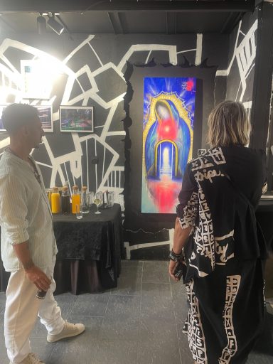 Deux personnes observant une œuvre d'art colorée représentant une figure sacrée.