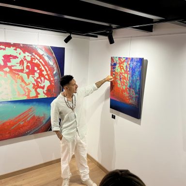 Un artiste montre une toile colorée dans une galerie d'art moderne.